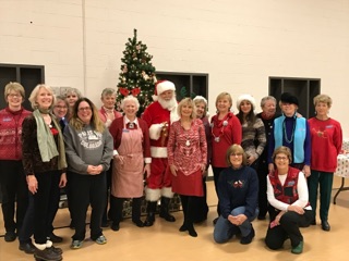 Group of service league members posing with Santa Clause