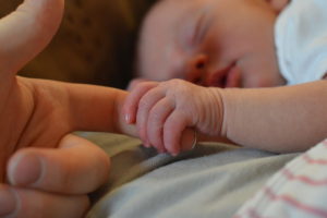 baby holding adult's finger