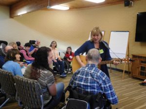 Susan makes her way around the room with her guitar, opening the music therapy session on a Tuesday in October.