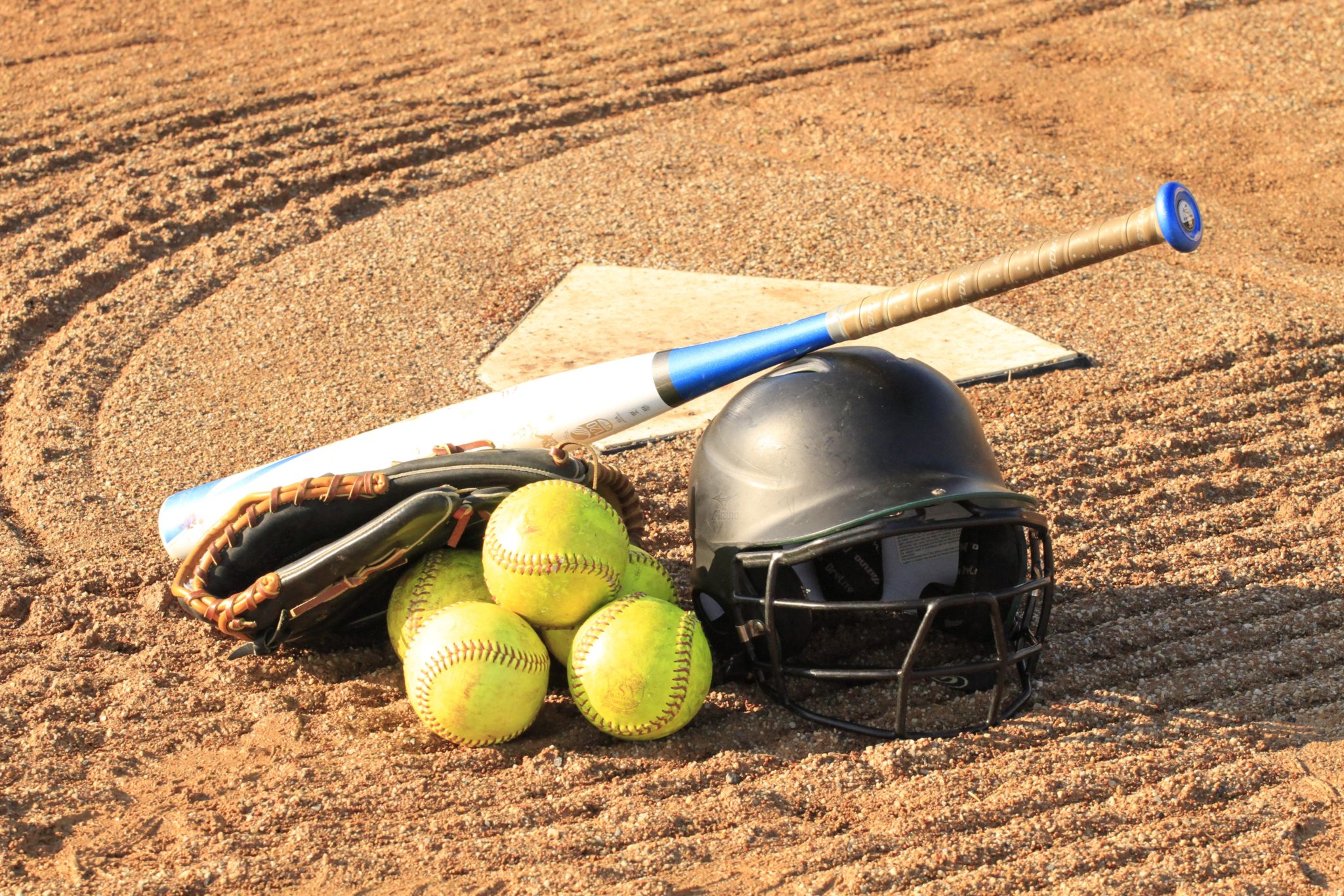 photo of softballs, bat and helmet on baseball diamond